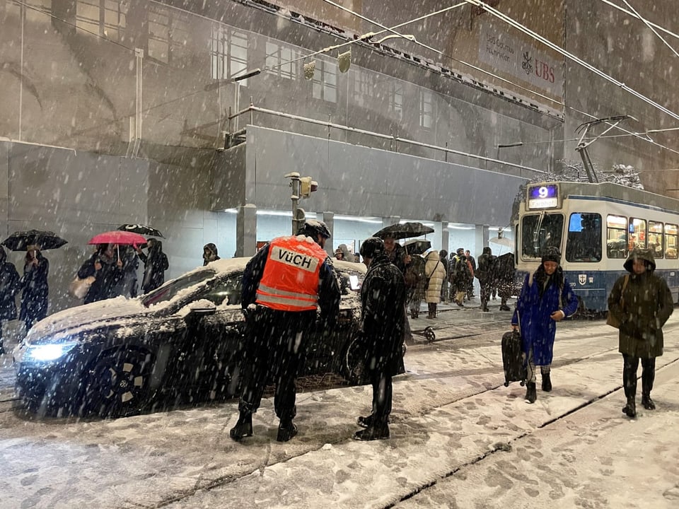 Strassenszene im Schneefall mit Strassenbahn und Passanten.