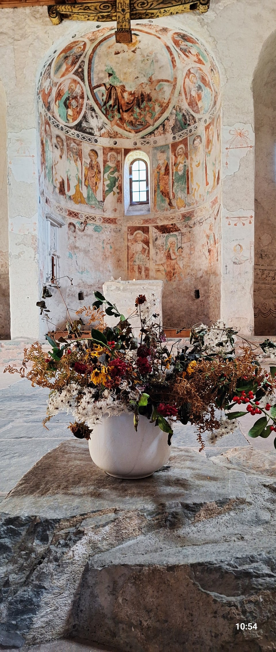 Kunstvoll bemalte Kapelle mit Blumenarrangement im Vordergrund.