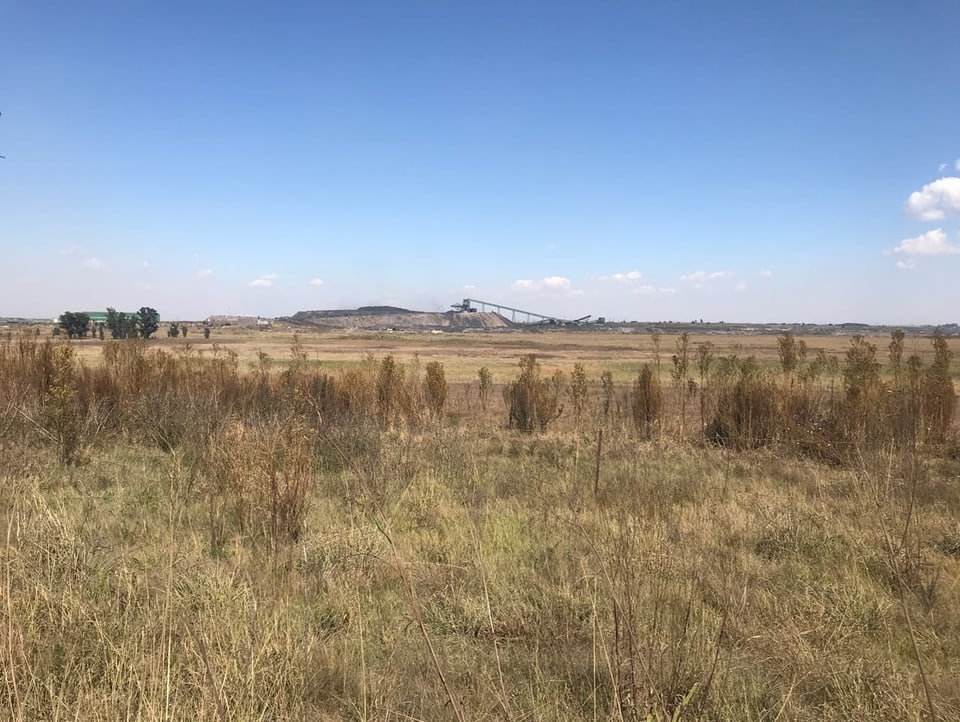 Aufnahme von einer Landschaft in Südafrika. In der Bildmitte ist eine Kohleabbau zu sehen.