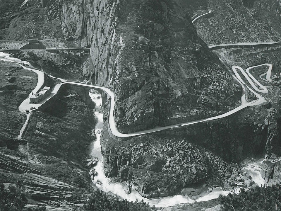 Historische Aufnahme der Schöllenenschlucht mit Serpentinenkurven und einer Eisenbahnbrücke. 