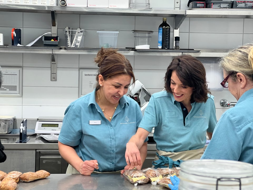 Mona Vettsch steht mit Sarra in der Grossküche. Sie lachen und packen Sandwiches ein.