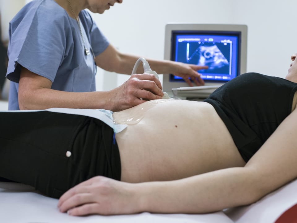 Ein Arzt führt eine Ultraschalluntersuchung bei einer schwangeren Frau durch.