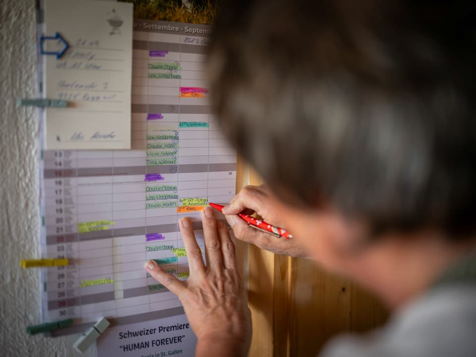 Person markiert Kalender mit rotem Stift.