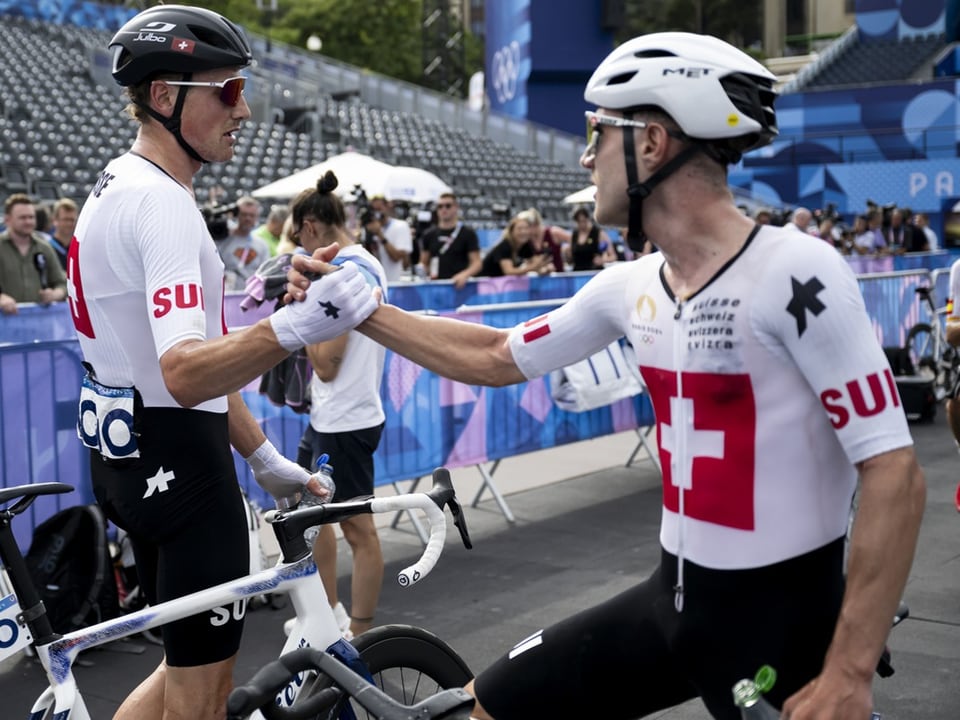 Zwei Radfahrer im Wettkampfanzug geben sich die Hand.