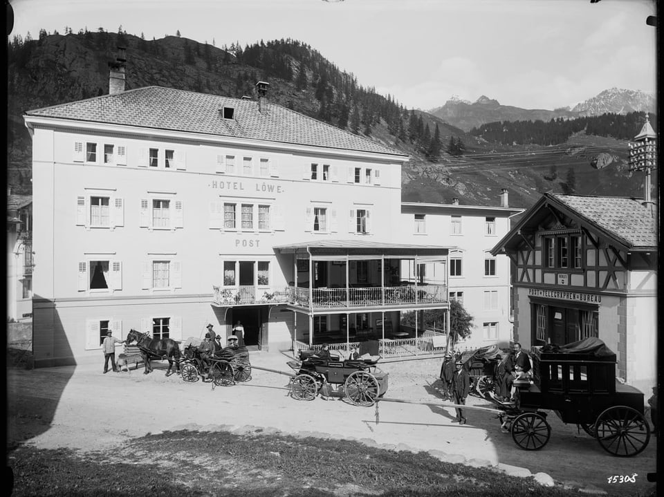 Historisches Hotel Löwe mit Pferdekutschen und Bergen im Hintergrund.