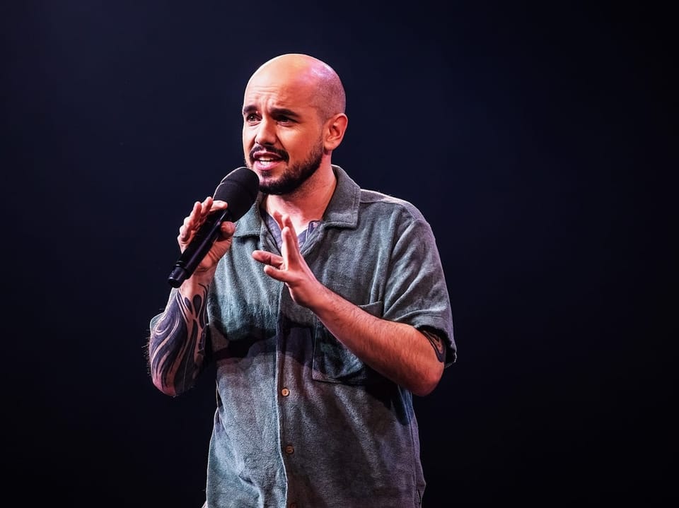 Komiker Renato Kaiser mit Mikrofon auf der Bühne.