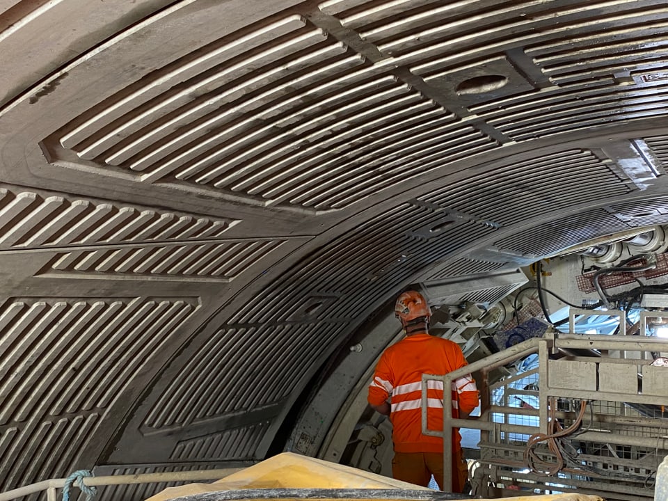 Arbeiter in einem Tunnel mit geripptem Metallgewölbe.