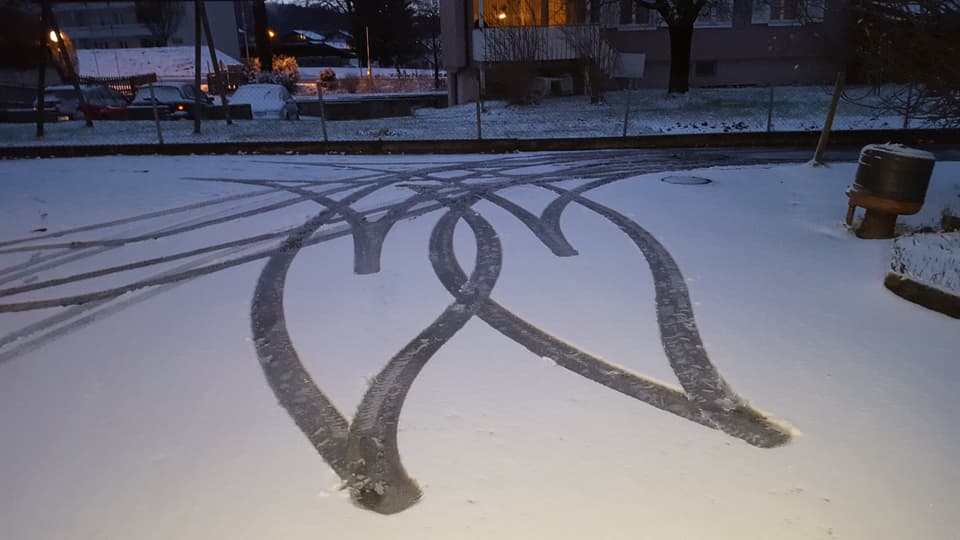 Reifenspuren im Schnee auf einem Parkplatz.