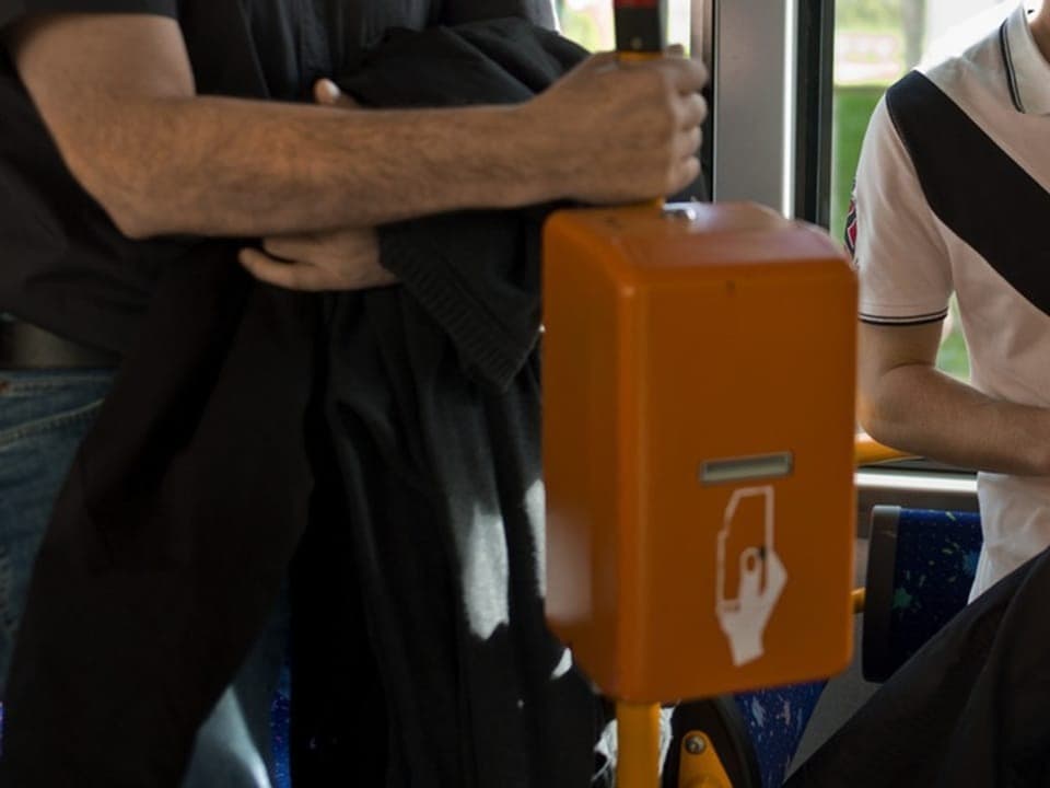 Zwei Personen an einem Fahrkartenentwerter in einem Bus.