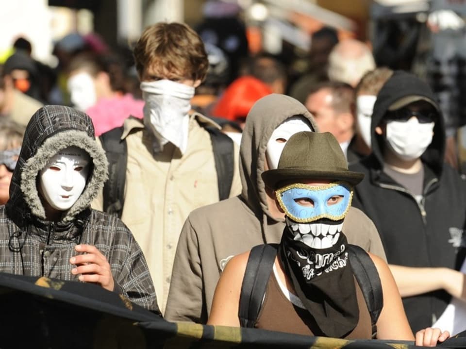 Menschen mit Masken bei einer Demonstration.