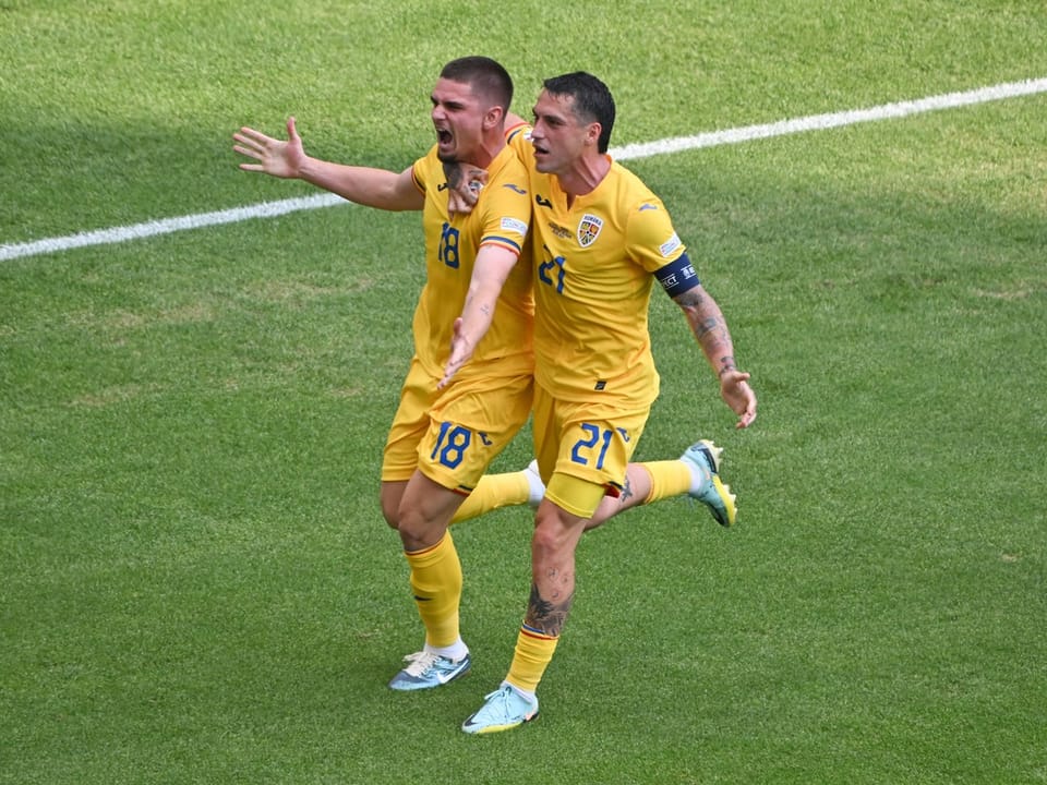Zwei Fussballspieler in gelben Trikots feiern auf dem Spielfeld.