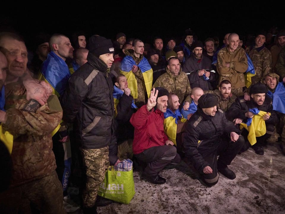 Gruppe von Männern mit ukrainischen Fahnen bei Nacht.