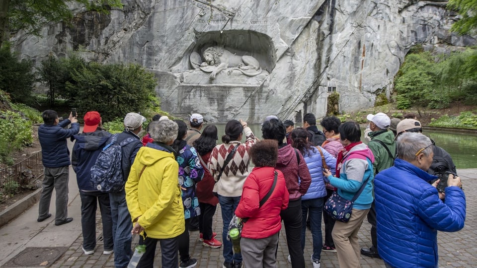 Touristen stehen vor dem Löwendenkmal in Luzern