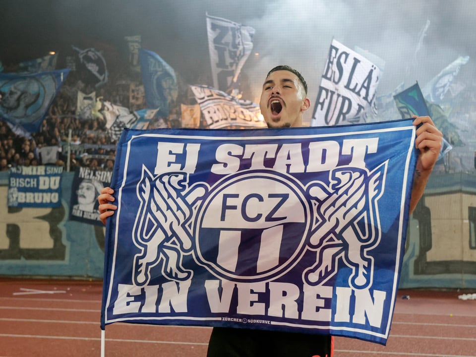 Fussballfan mit blauem Banner im Stadion.