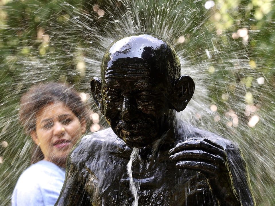 Person neben spritzender Statue im Freien.