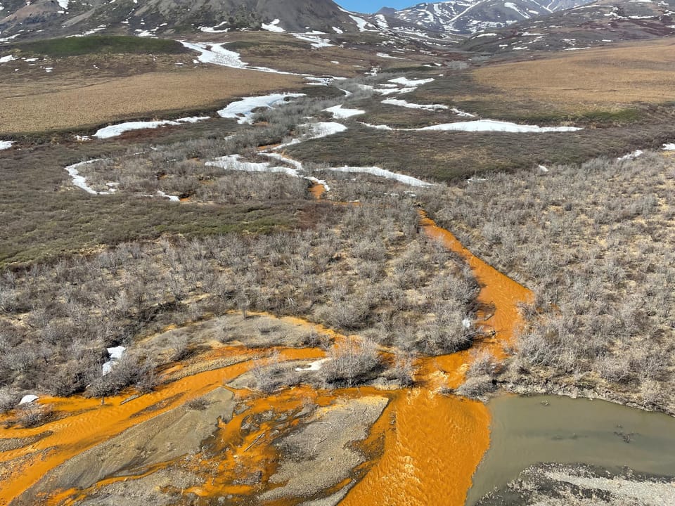 Ein Zufluss mit orange-Färbung in einer Landschaft.