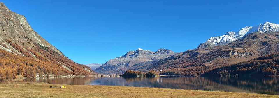 Berglandschaft mit klarem See und schneebedeckten Gipfeln.