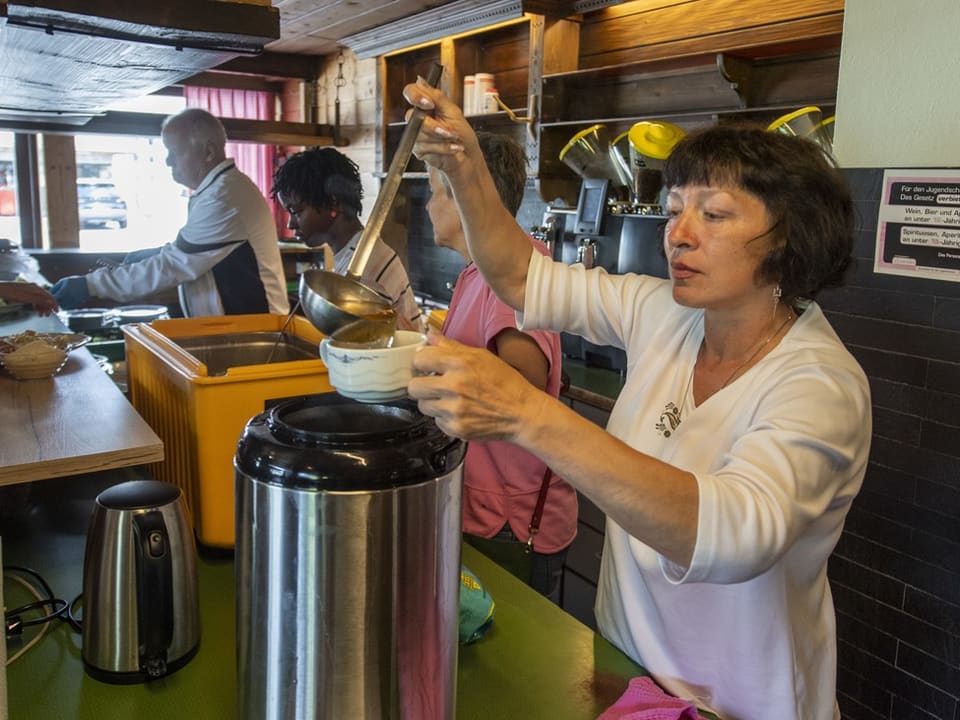 Frau schöpft Suppe in eine Schüssel in der Küche.