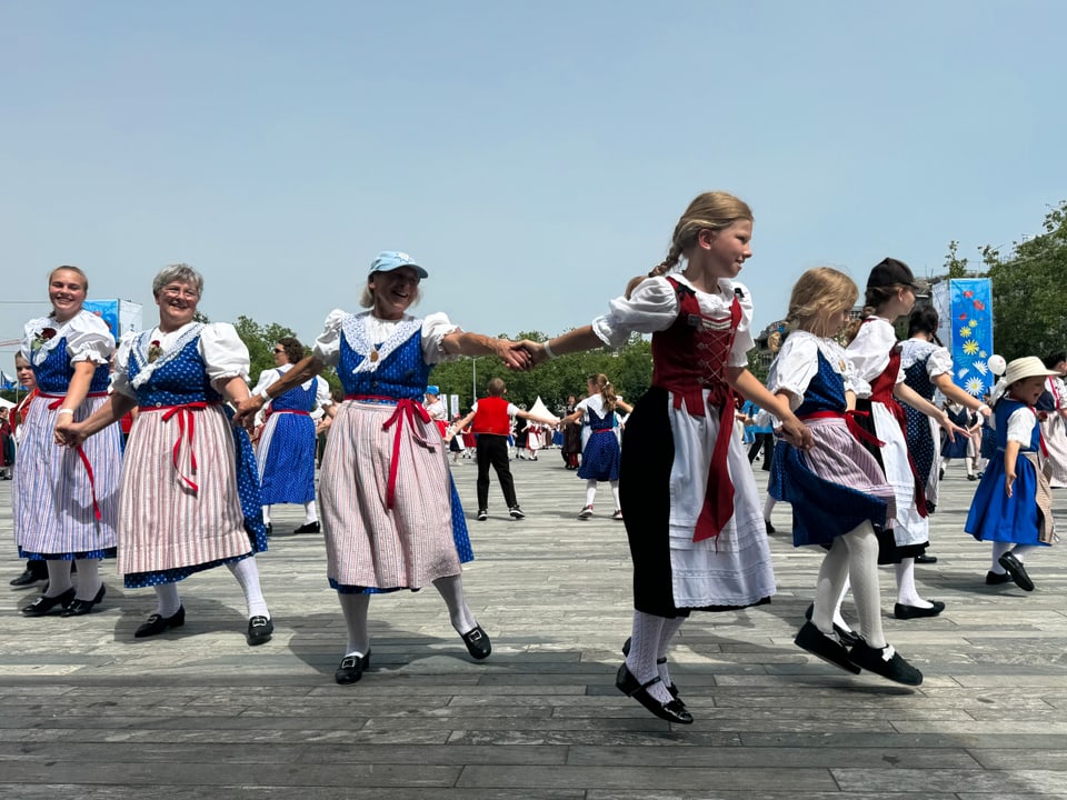 Eine Gruppe Mädchen und Frauen tanzen in Trachten