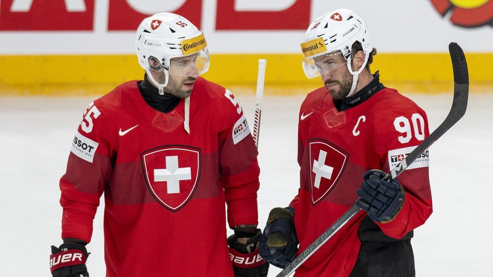 Zwei Eishockeyspieler in roten Trikots mit Schweizer Flagge.