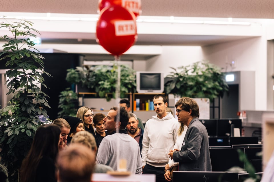 Gruppe von Menschen in einem Büro mit roten Luftballons.