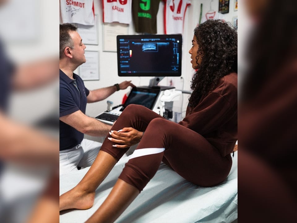 Arzt untersucht das Bein einer Patientin mit Ultraschallgerät.
