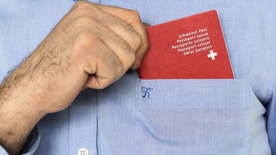 Person steckt Schweizer Pass in Hemdtasche.