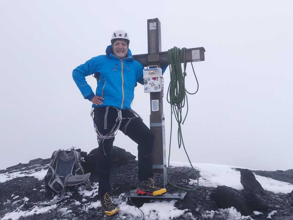 Alpinist am Gipfelkreuz des Piz Russein, 3612 Meter über Meer.