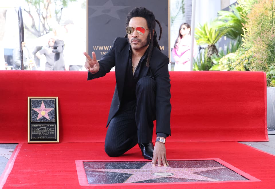 Lenny Kravitz posiert hockend mit seinem Stern auf dem Hollywood Walk of Fame.