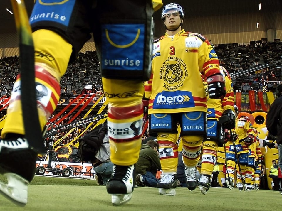 Eishockeyspieler in gelben Trikots betreten das Spielfeld.