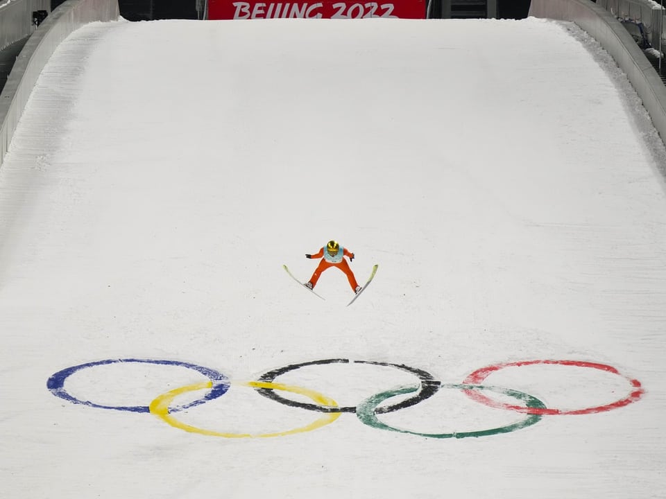 Skispringer über olympischen Ringen bei den Olympischen Winterspielen 2022 in Peking.