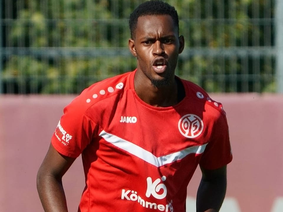 Fussballspieler im roten Trainingsanzug auf dem Spielfeld.