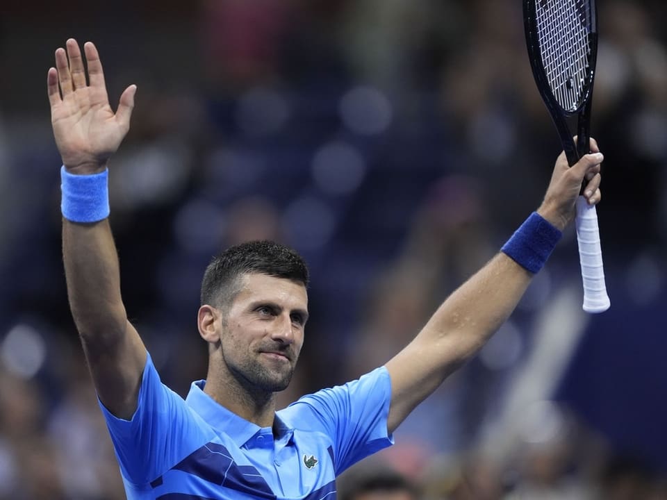 Tennisspieler hebt Arme zur Siegesfeier auf dem Platz.