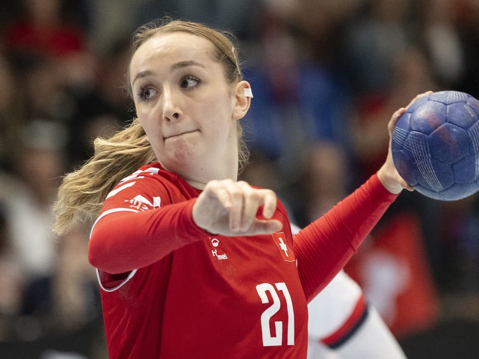 Handballspielerin in rotem Trikot mit Ball in Aktion.