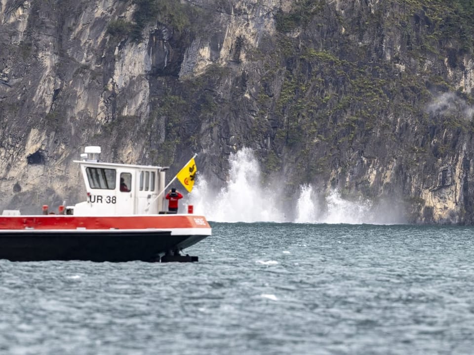 Boot auf dem See vor Felsenküste mit Wellengang.