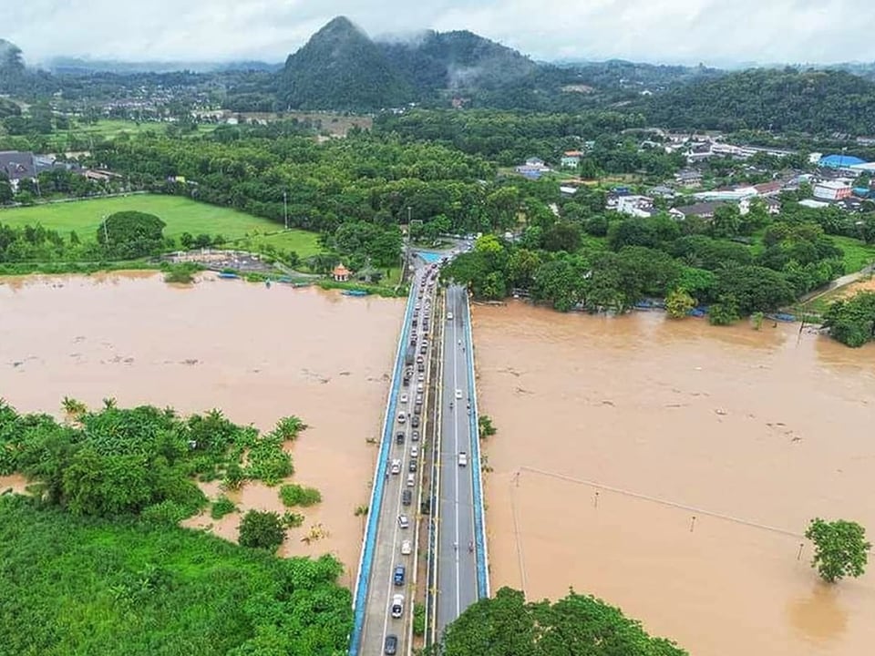 Luftaufnahme einer überfluteten Landschaft mit einer Brücke und Autos.