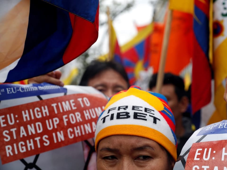 Foto eines Kopfes mit einer Kappe, worauf «Free Tibet» steht. Im Hintergrund sind andere Protestierende zu sehen.