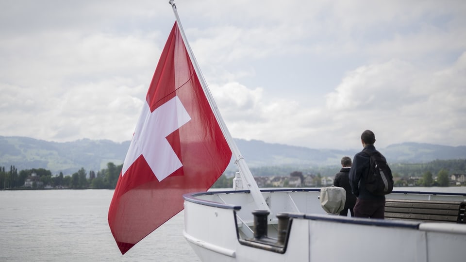 Zwei Personen schauen vom Heck eines Schiffes auf das Ufer.