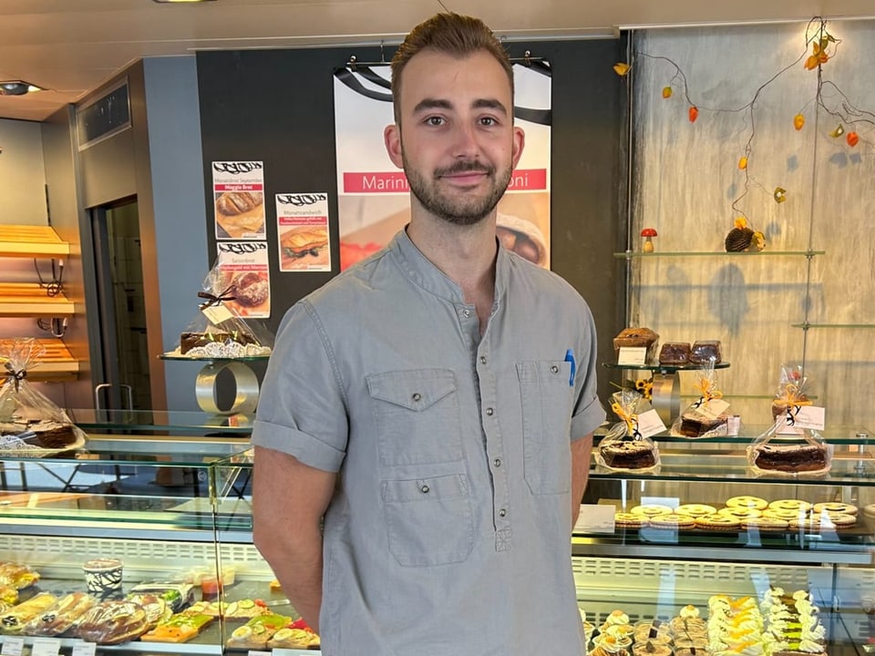 Mann in einer Bäckerei vor einer Vitrine mit Gebäck.