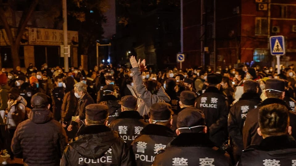 Protestierende Menschen und Polizisten in Beijin.