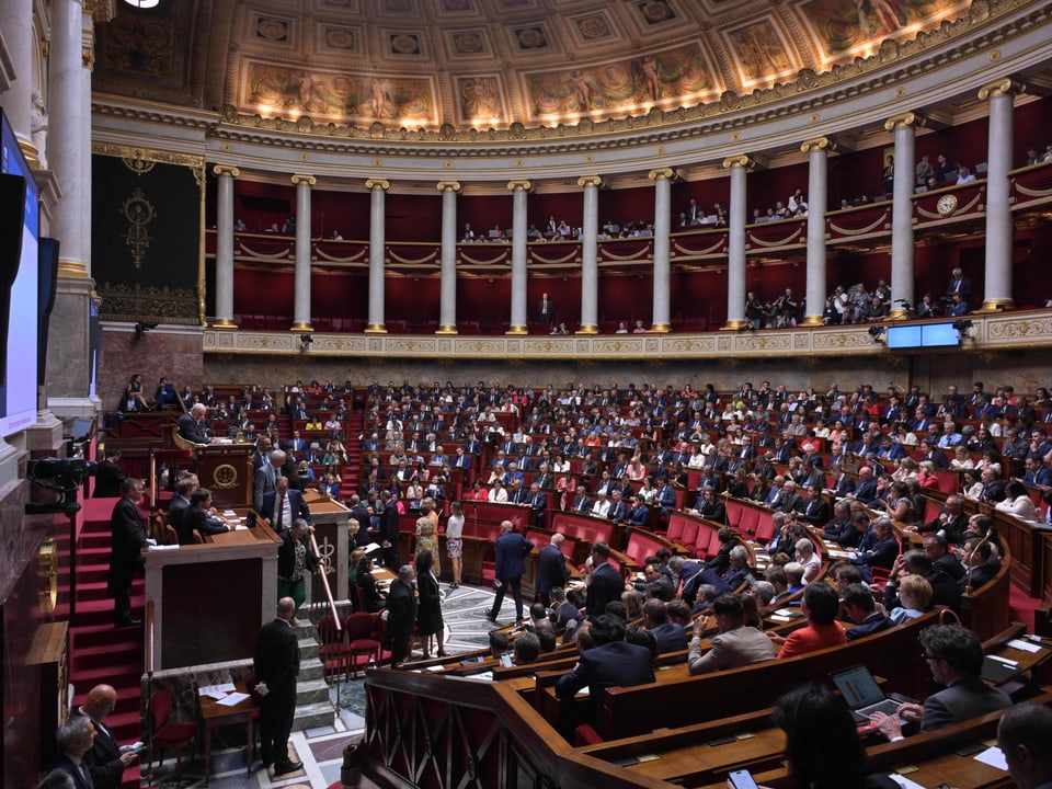 Volles Auditorium in einem prunkvollen Saal.