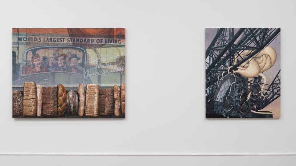 Zwei Gemälde an der Wand, links mit einer Reihe von Brotlaiben, rechts mit einer Industrieszene..