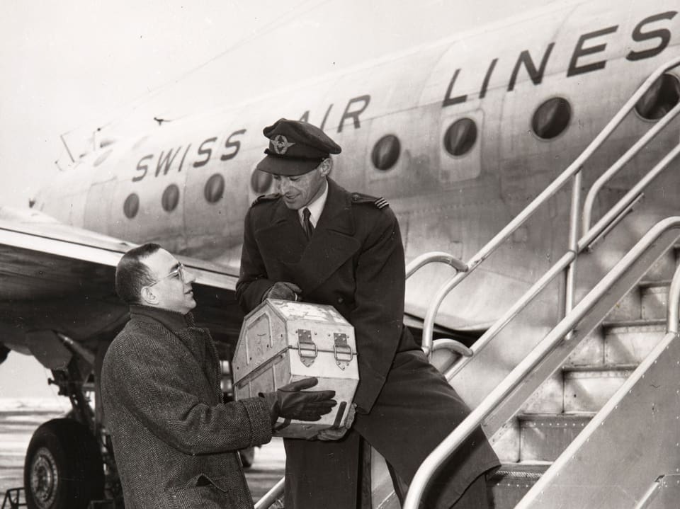 Transport von Filmrollen vor einem Swissair-Flugzeug 1945.