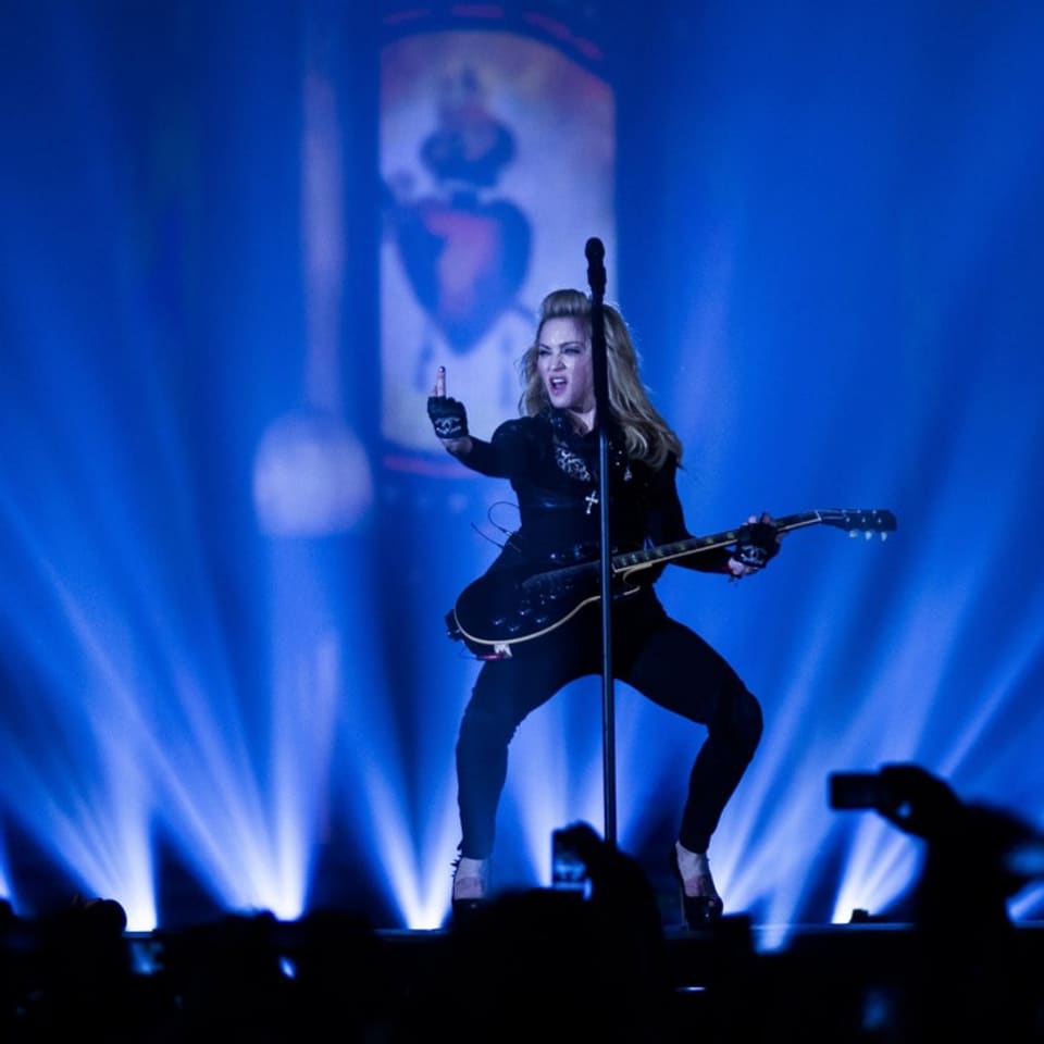 Frau auf Bühne mit Gitarre und zeigt den Mittelfinger