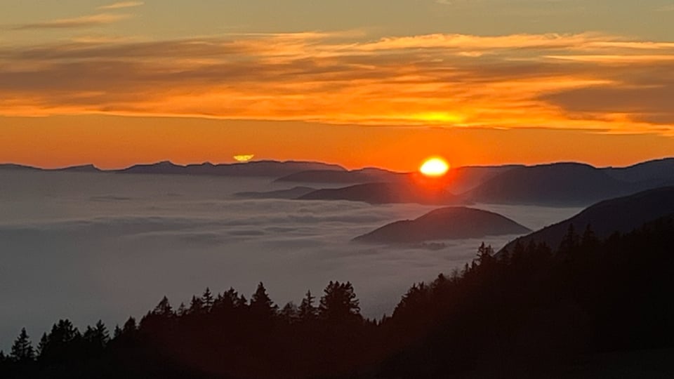 Blick auf ein Nebelmeer und einen Sonnenuntergang.