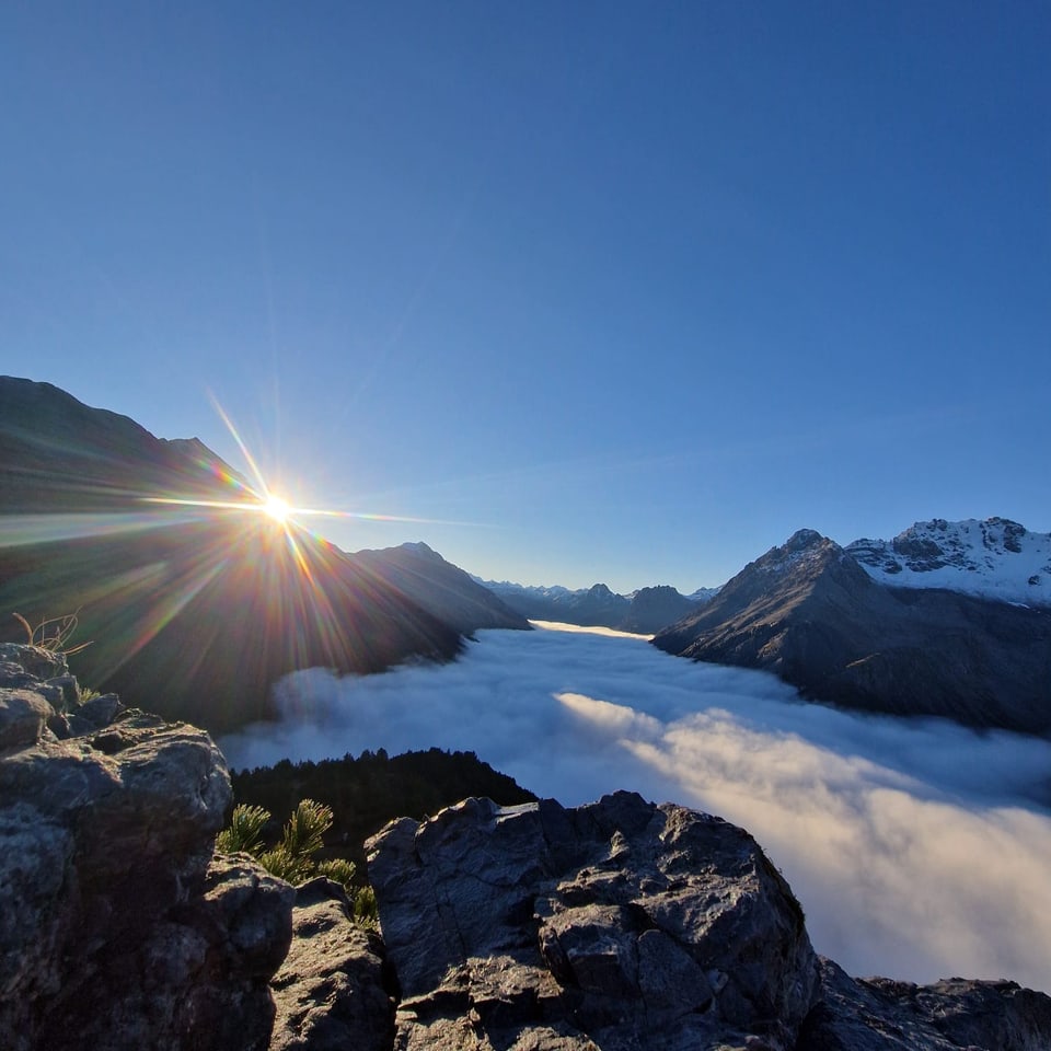 Berglandschaft bei Sonnenaufgang über Wolken.