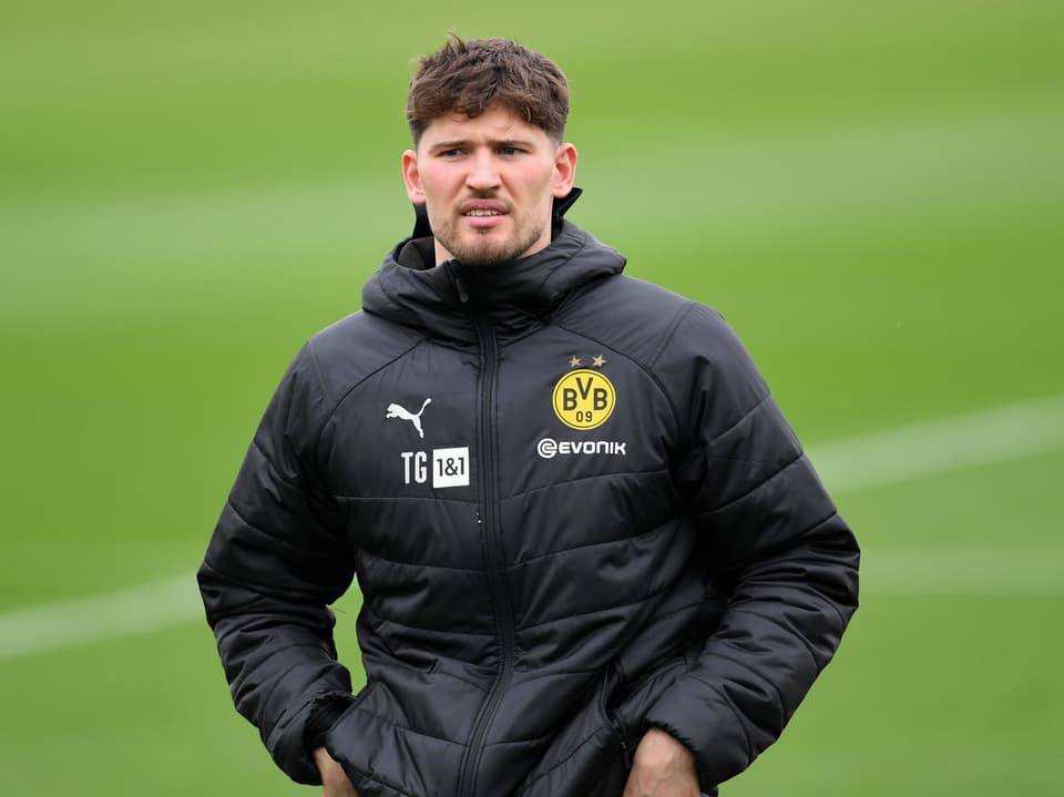 Mann in BVB-Trainingsjacke auf Fussballplatz.