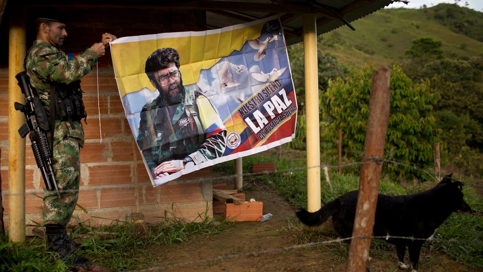 Ein Farc-Rebelle hängt ein Plakat auf, darauf steht: «Unser Traum ist Frieden mit sozialer Gerechtigkeit»