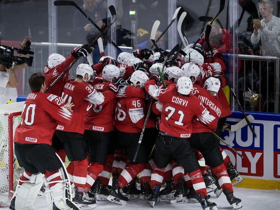Eishockeymannschaft in roten Trikots feiert auf dem Eis.