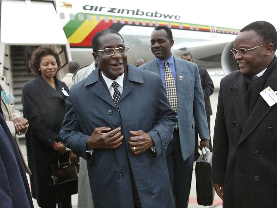 Mugabe mit Begleitern am Flughafen.